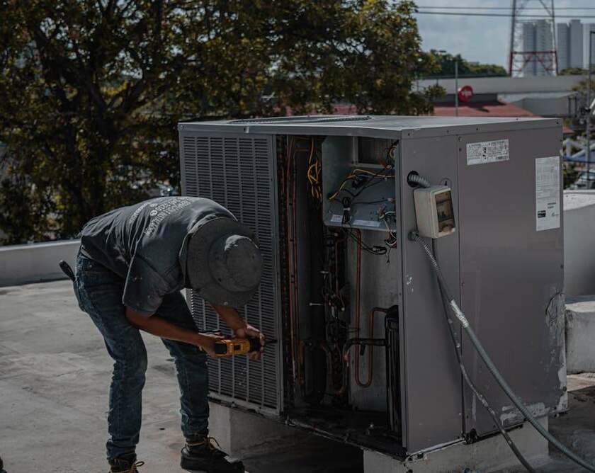 HVAC technician making a repair on a rooftop unit