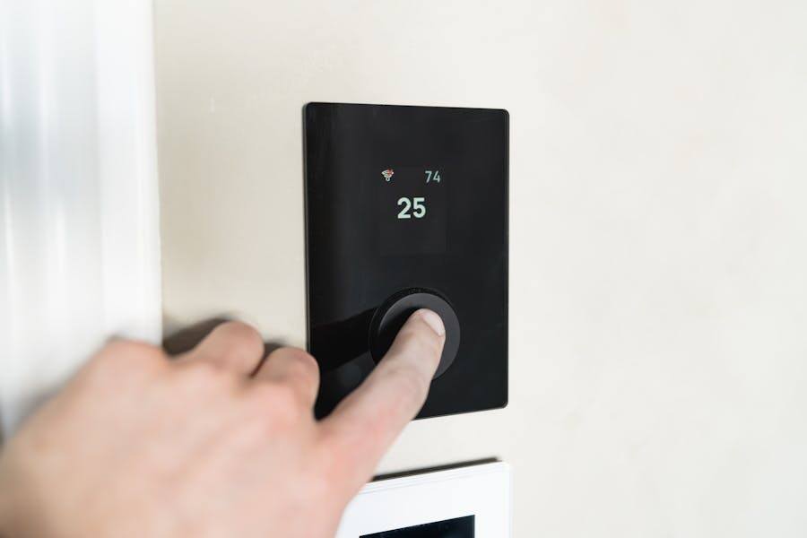 Hand adjusting a smart thermostat for home climate control